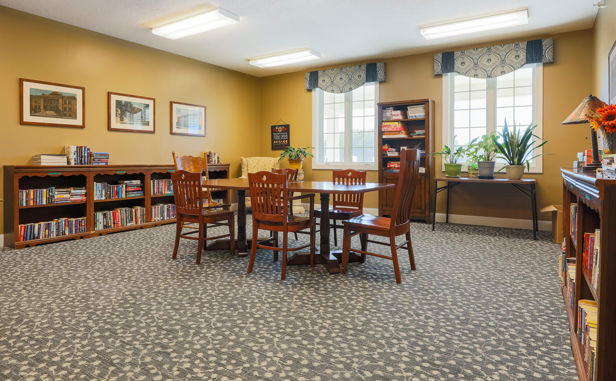 A cozy library reading room with tables and chairs surrounded by bookshelves.