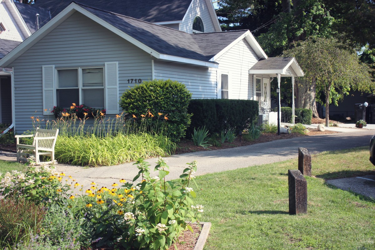 A quaint house with a well-maintained garden and a driveway.