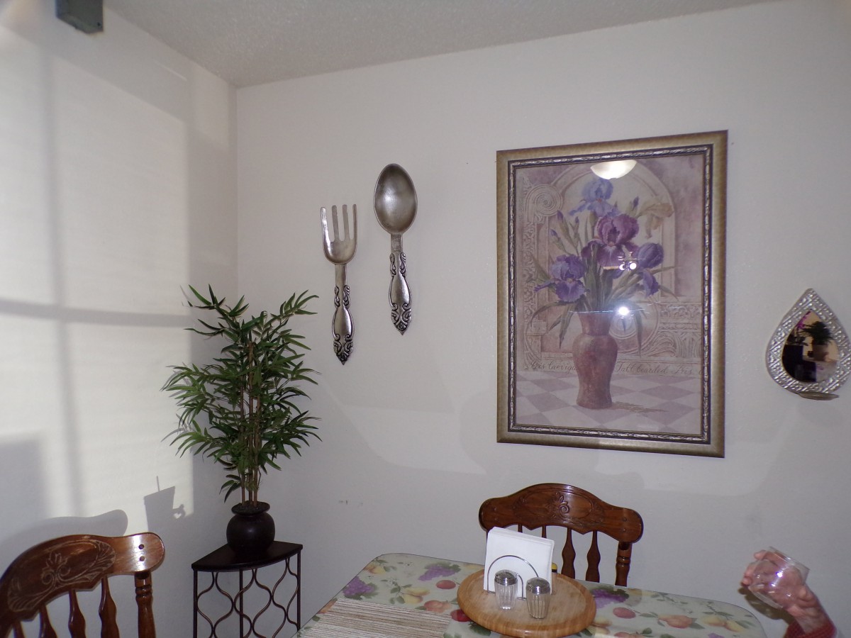 A cozy dining area with large utensils and floral artwork on the wall.
