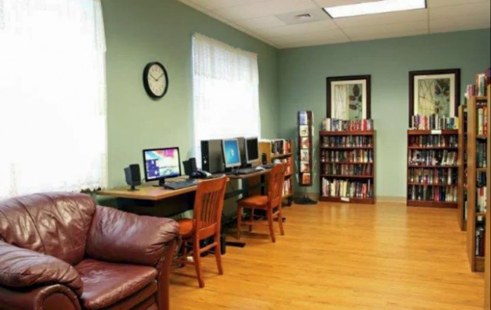 A cozy computer room with several computers, bookshelves, and comfortable seating.