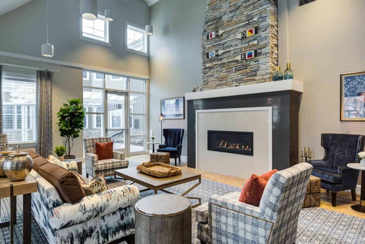 A modern living room with a high ceiling, featuring a stylish fireplace and large windows.