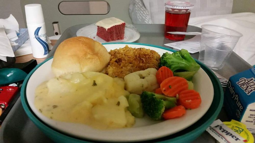 A hospital meal with mashed potatoes, vegetables, fried chicken, and a bread roll.