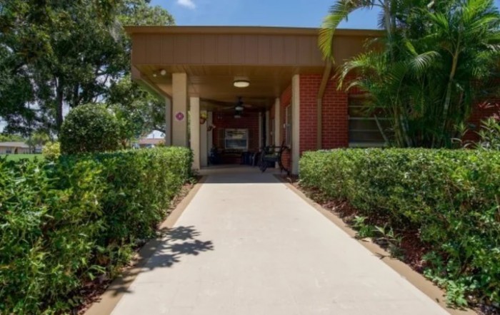 A building entrance surrounded by neatly landscaped plants and a clear pathway on a sunny day.