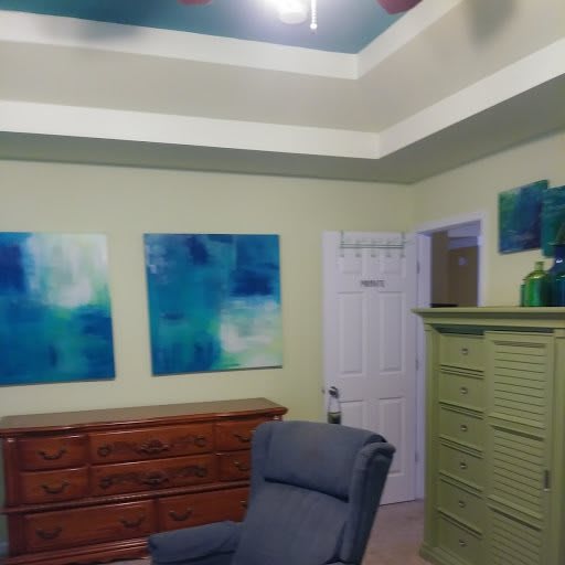 A room featuring blue artwork, a comfortable chair, and wooden furniture.