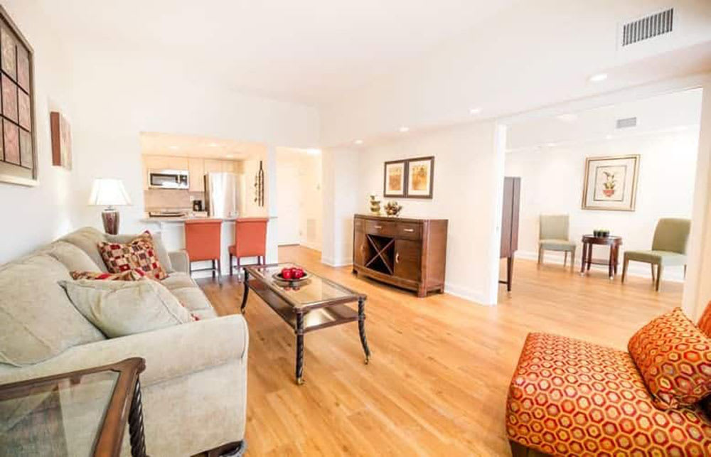A bright and spacious living room with modern furniture and wood flooring.