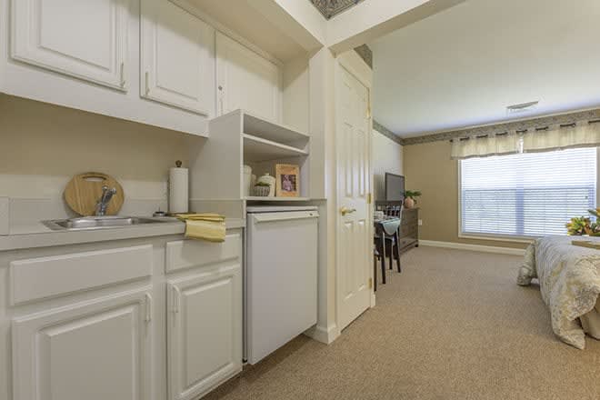 A small kitchen area opens into a cozy living room with a window.