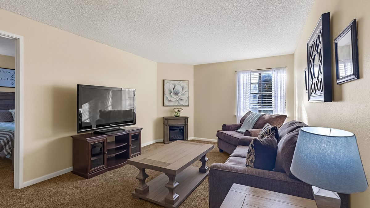 A cozy living room with a large television, comfortable sofas, and a wooden coffee table.