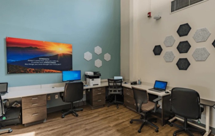 A modern office space with multiple workstations equipped with computers and a printer.