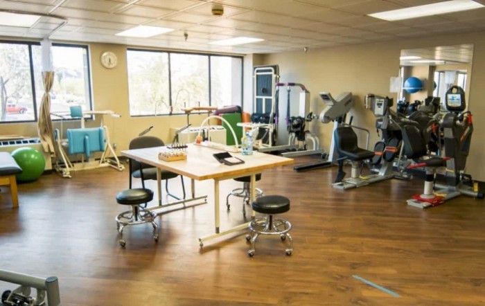 A rehabilitation room equipped with various exercise machines and therapy tables.