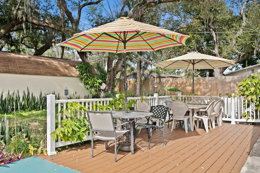 Outdoor patio area with tables, chairs, and umbrellas on a wooden deck.