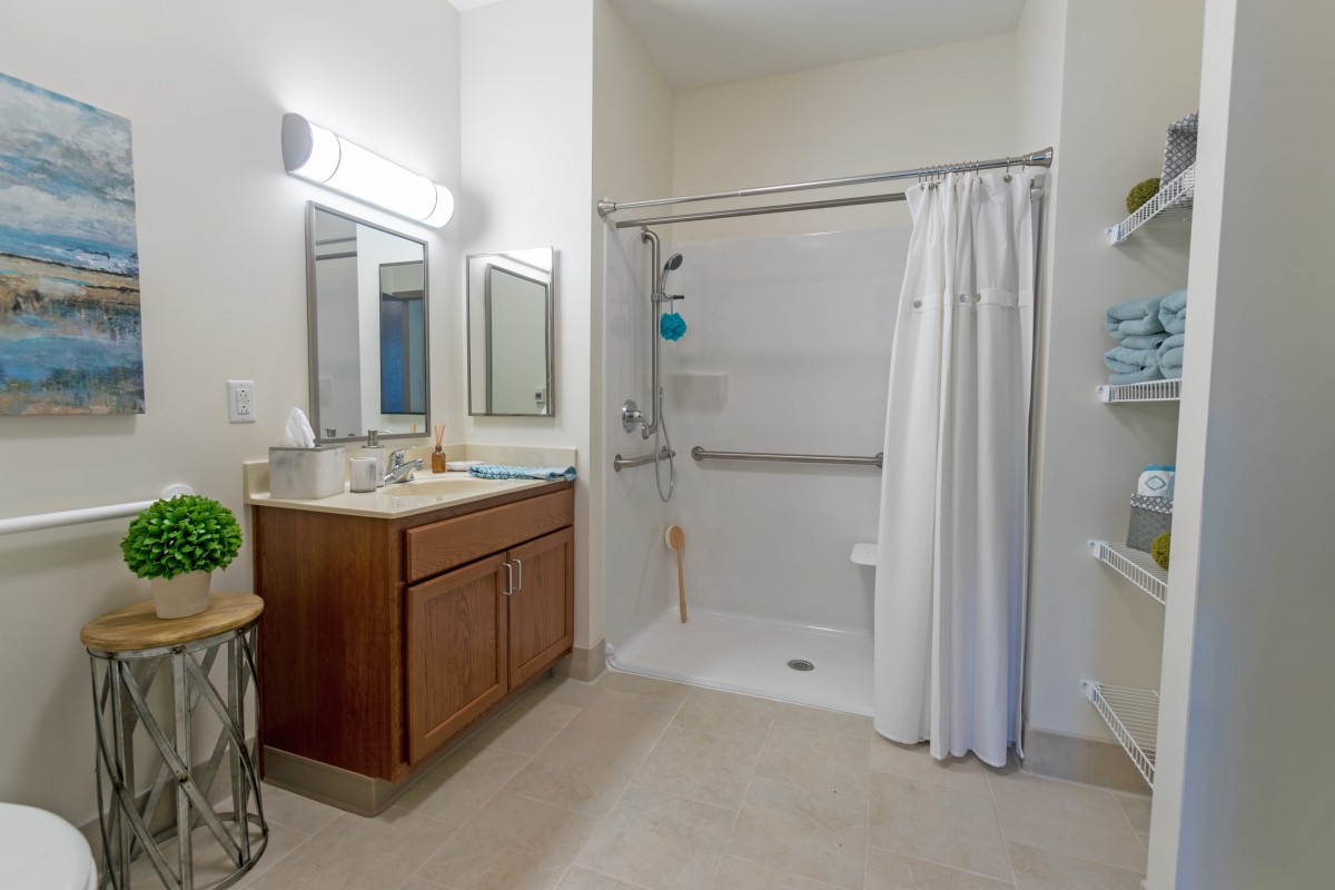 A modern bathroom with a shower, white curtain, and wooden cabinet sink.