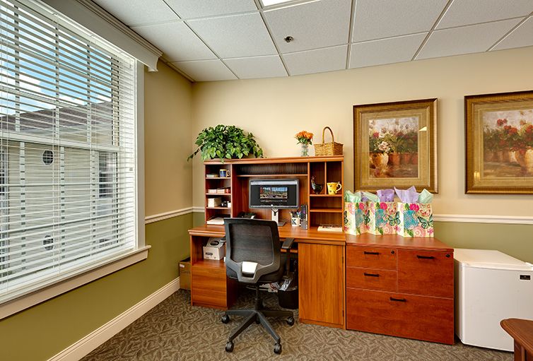 A neatly organized office with a desk, chair, and computer by a window.