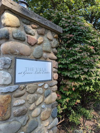 A beautifully crafted stone wall with a sign, surrounded by lush greenery.