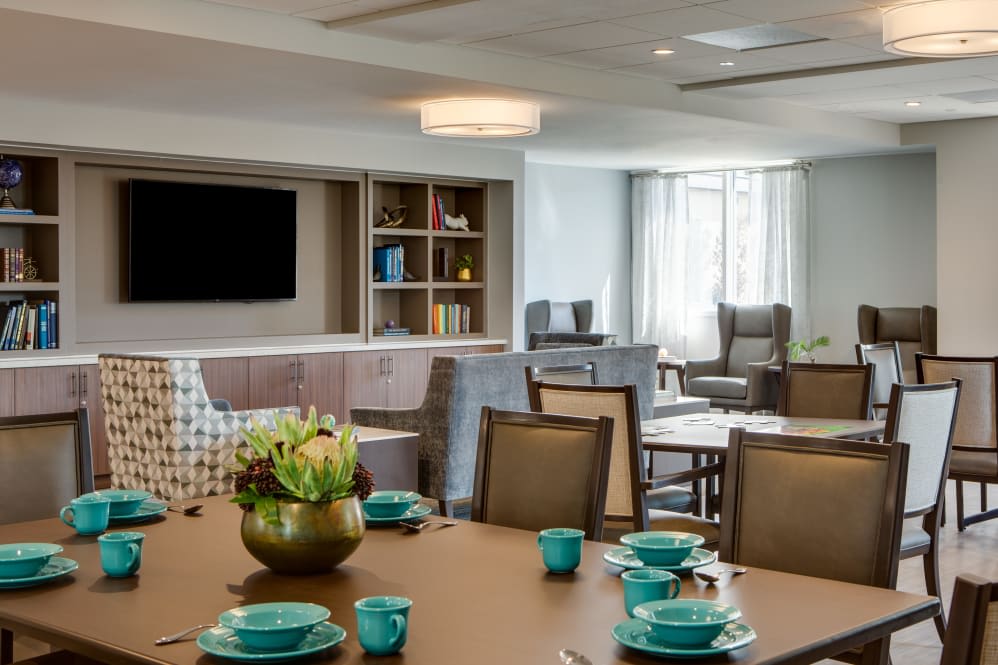 A modern living and dining area with contemporary decor, featuring a table set with turquoise dishes.