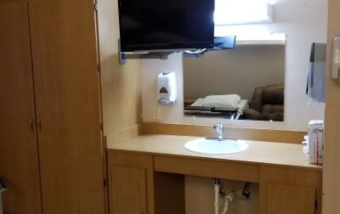 A bathroom sink area with a wall-mounted TV and a cabinet.