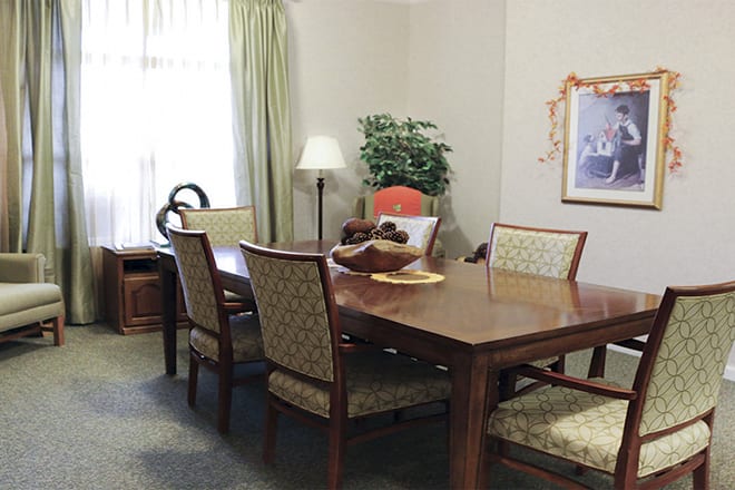 A dining room with a wooden table and chairs, adorned with decorative items and a plant.