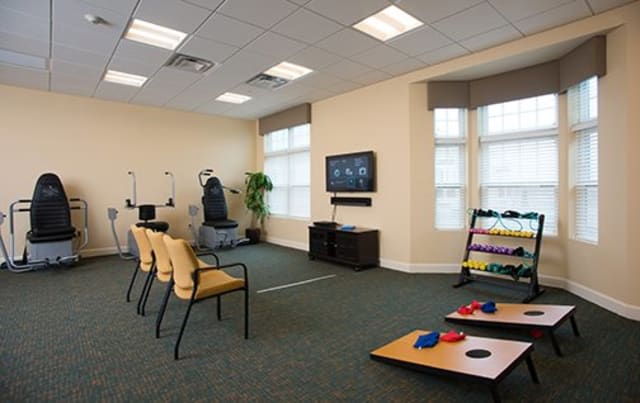 A bright and spacious waiting area with seating, a TV, and exercise equipment.
