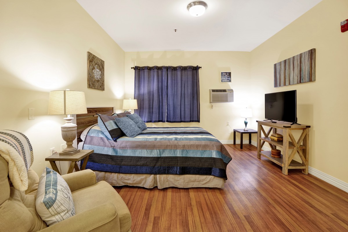 A cozy bedroom with two beds, soft lighting, and wooden flooring.