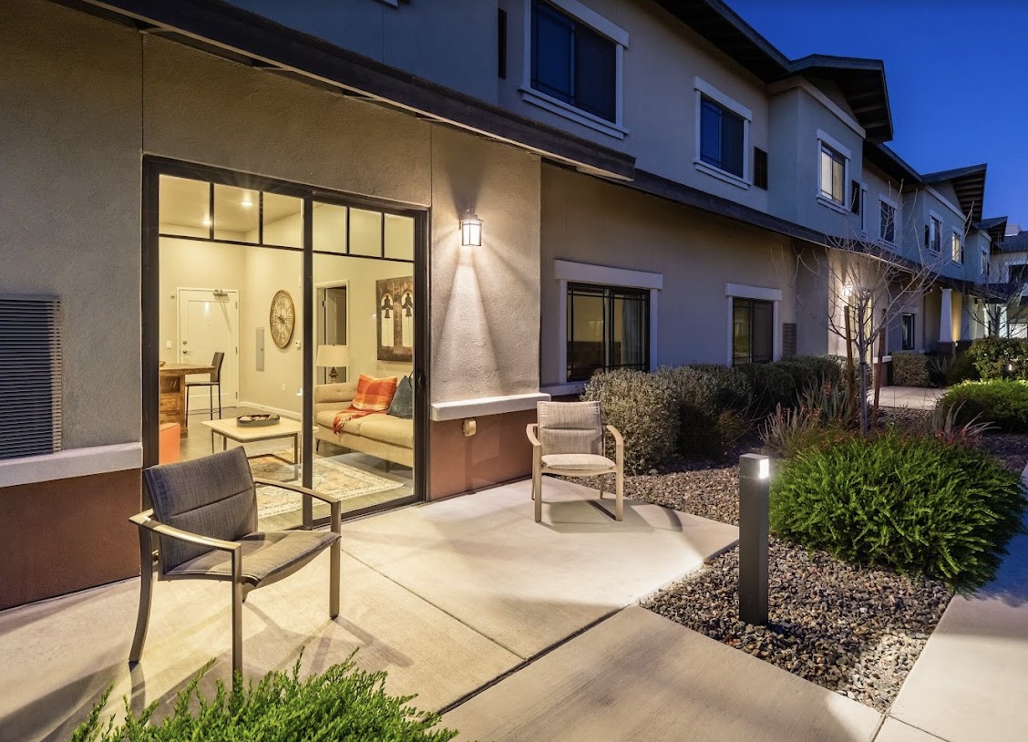 A modern residential patio with outdoor seating, illuminated at night.