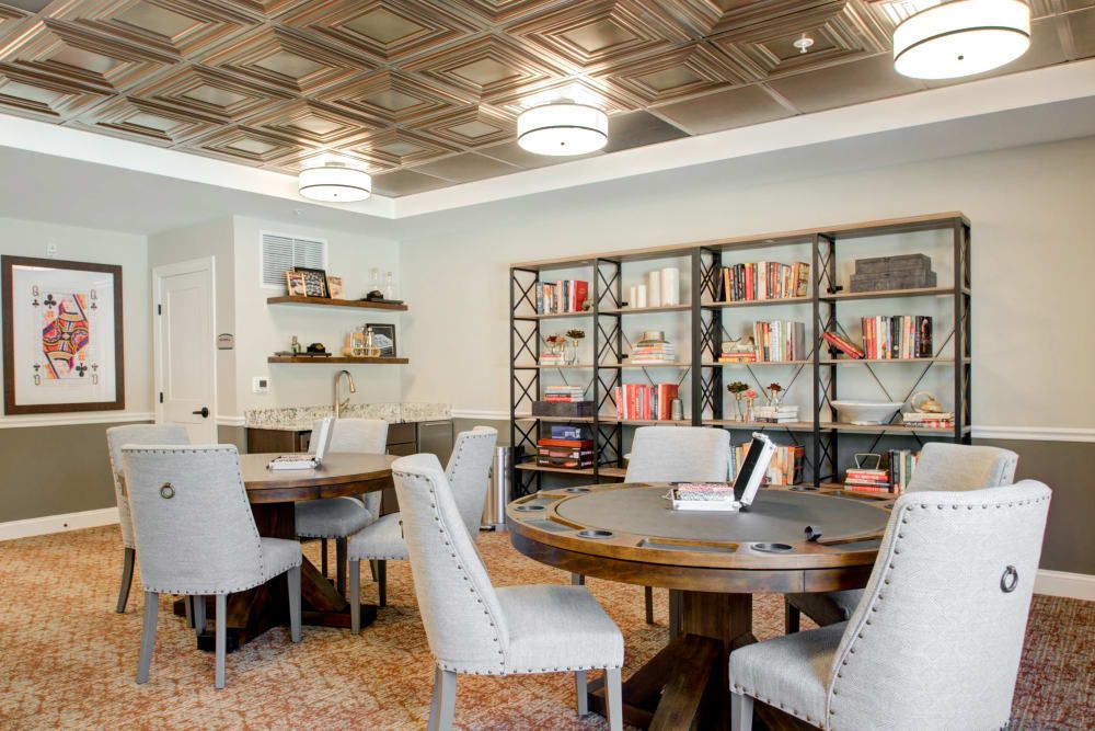A modern office space featuring round tables, comfortable chairs, and well-organized bookshelves.