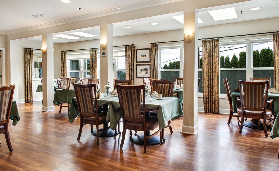 An elegant dining area with wooden flooring and well-arranged tables and chairs.
