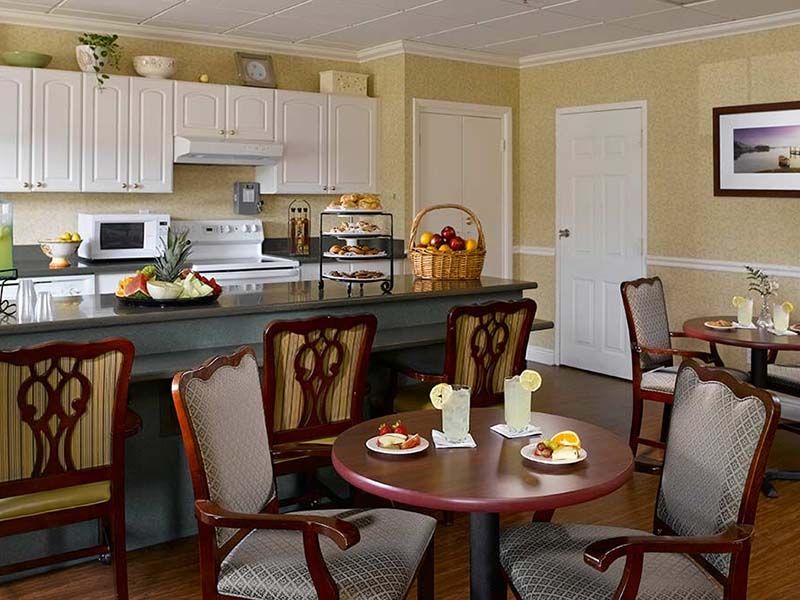 A cozy kitchen and dining area with tables set, chairs, and kitchen appliances.