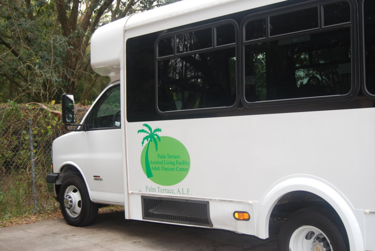 A white shuttle bus with a green palm tree logo on its side.
