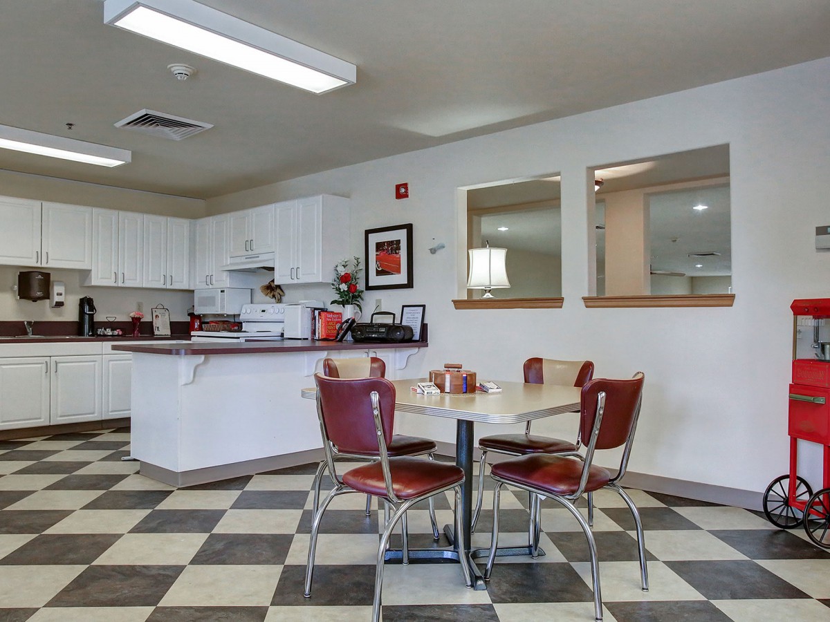 A classic diner setting with retro red chairs and a checkered floor, featuring a cozy kitchen area.
