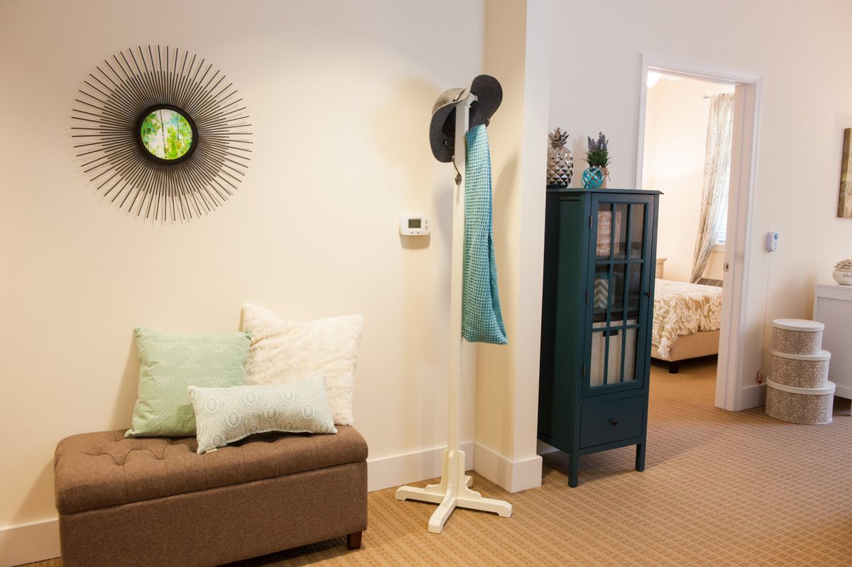 A cozy living room with a modern coat rack, stylish cushions, and decorative artwork on the wall.