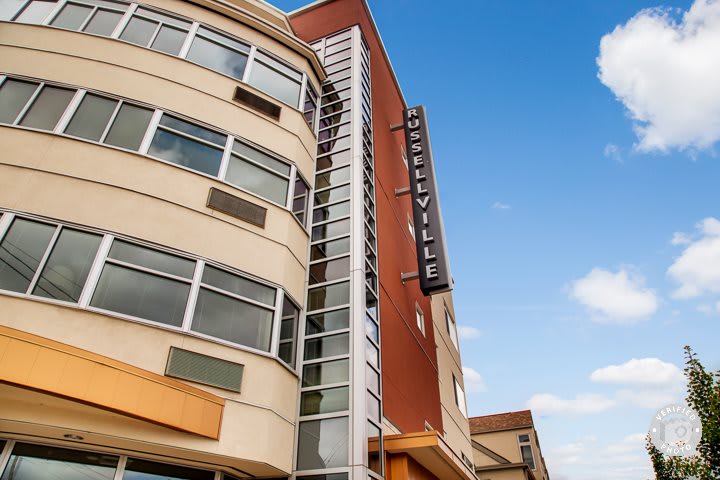 A modern urban building with a prominent sign against a clear blue sky.