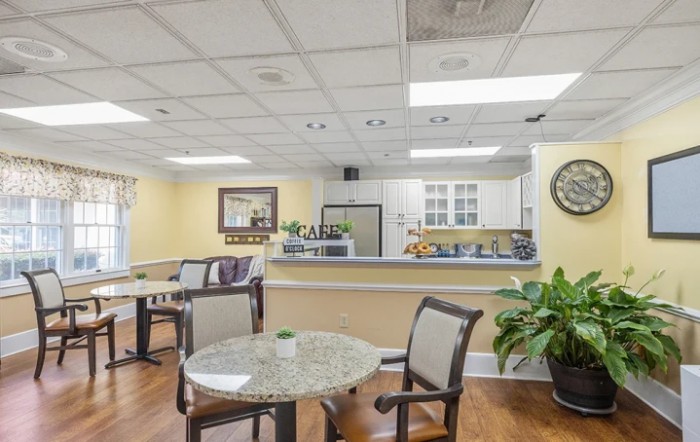 A cozy dining area with tables, chairs, and a view of the kitchen.
