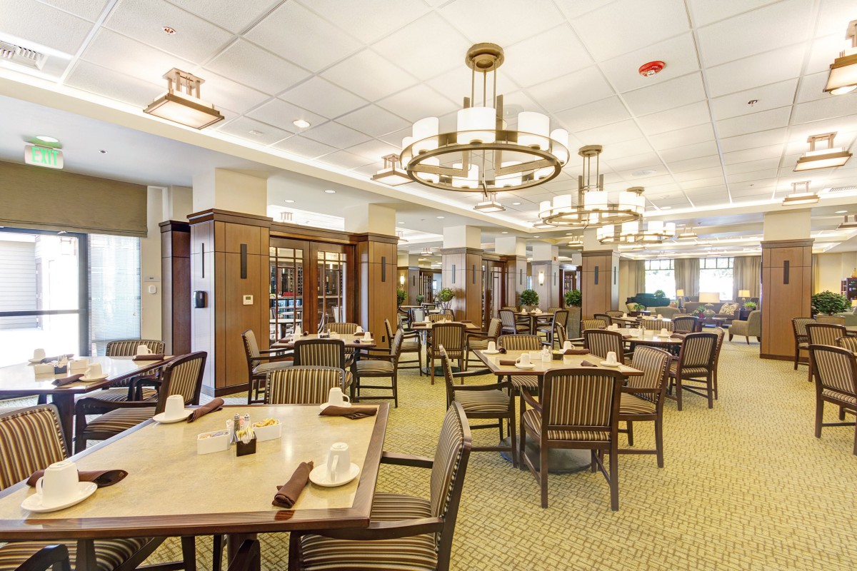 Spacious dining room with elegant chandeliers and well-arranged tables and chairs.
