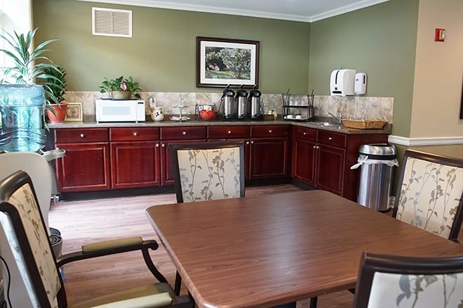 A cozy dining area with a kitchen setup, featuring wooden cabinets and a coffee station.