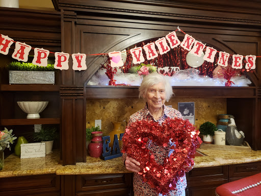 A cheerful elderly woman holding a heart-shaped decoration in celebration of Valentine's Day.