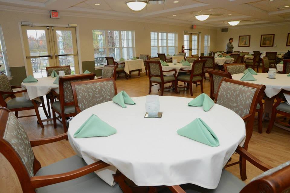 A neatly arranged dining room with tables set for service, featuring white tablecloths and folded napkins.