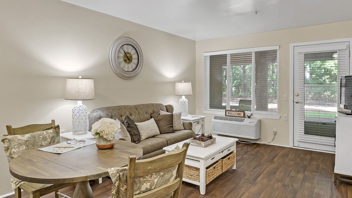 A cozy living room with a sofa, coffee table, and decorative elements including a wall clock and lamps.