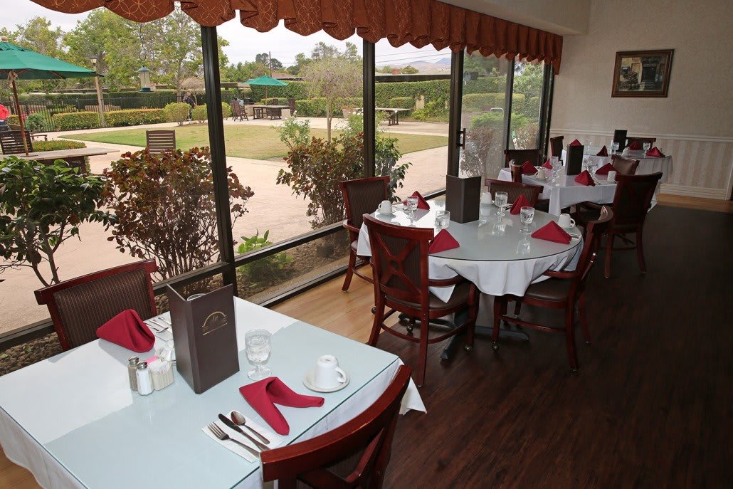 A cozy restaurant dining area with neatly arranged tables and a scenic window view.