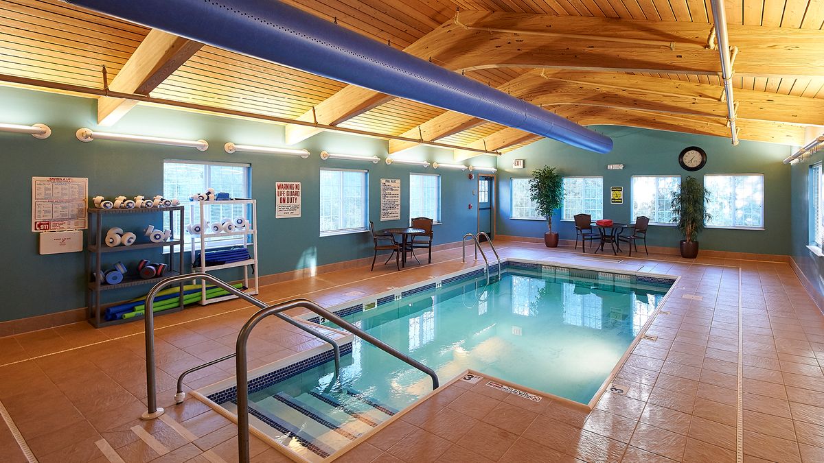 An inviting indoor swimming pool area with seating and a wooden ceiling.