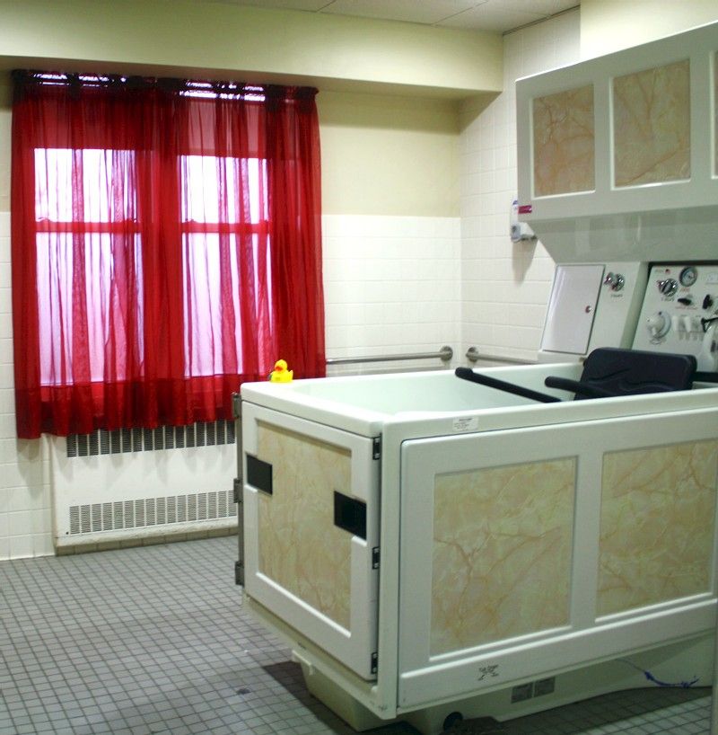 A room with a bathtub and red curtains covering a window.