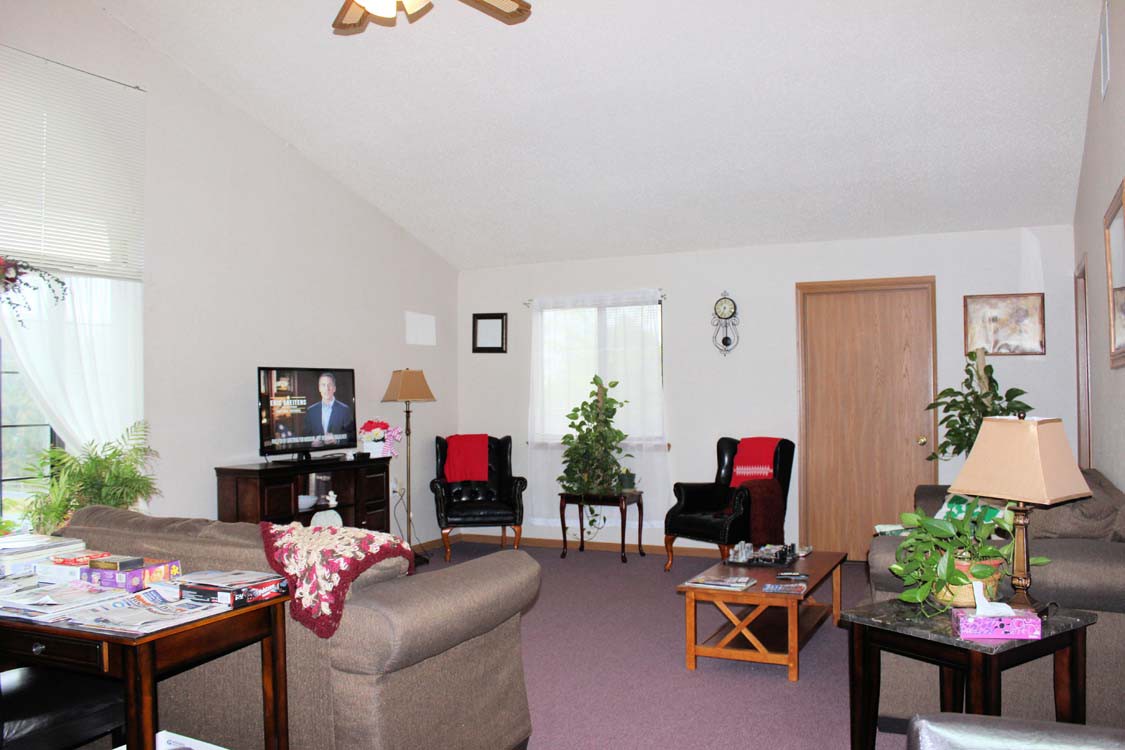 A cozy living room with a sofa, chairs, and a television.