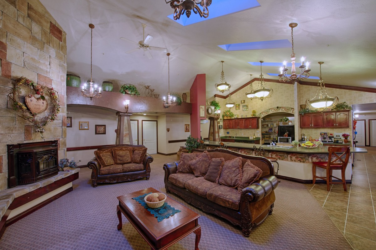 A spacious living room with adjacent kitchen, featuring elegant furniture and chandeliers.