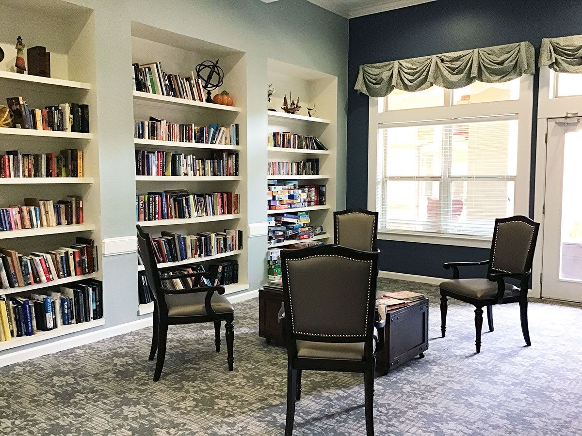 A cozy library space with bookshelves and seating near a large window.