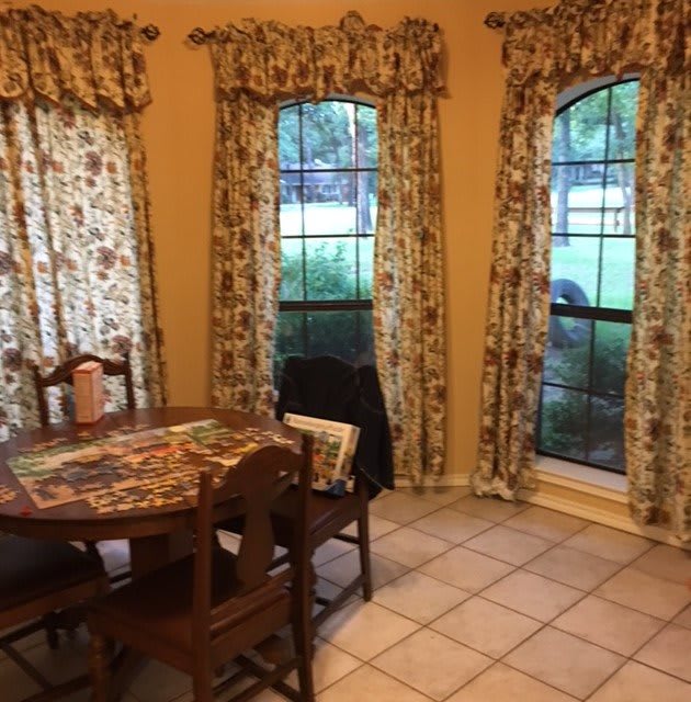 A cozy dining area with a round table and patterned curtains by the windows.