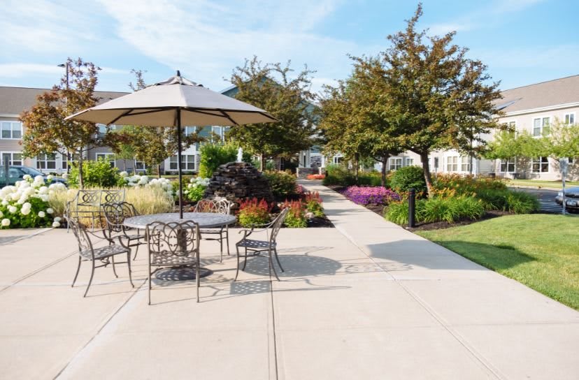 A beautifully landscaped outdoor patio area with tables, chairs, and an umbrella.