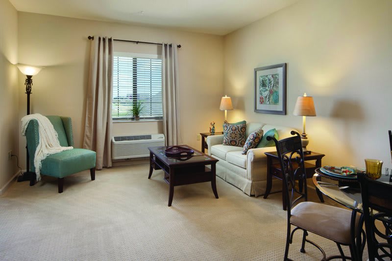 A cozy living room with a sofa, coffee table, and an armchair near the window.