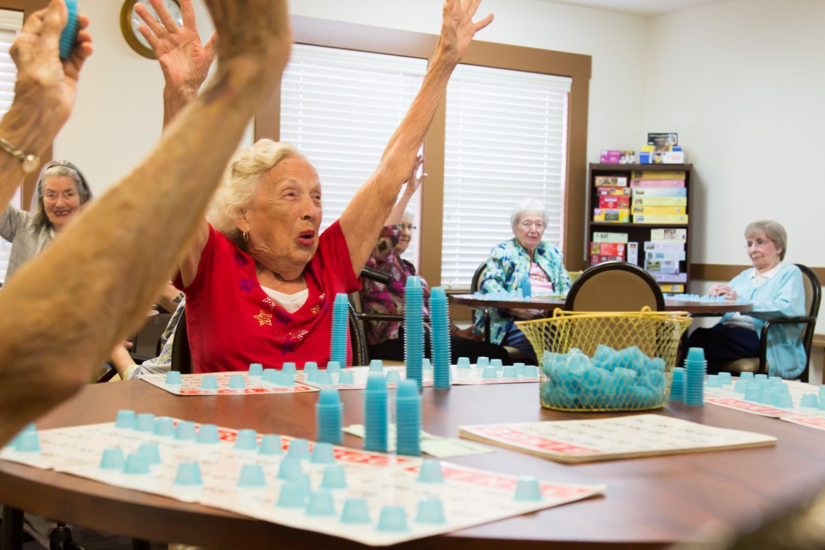 Seniors enjoying a lively board game session, with one participant celebrating their win.