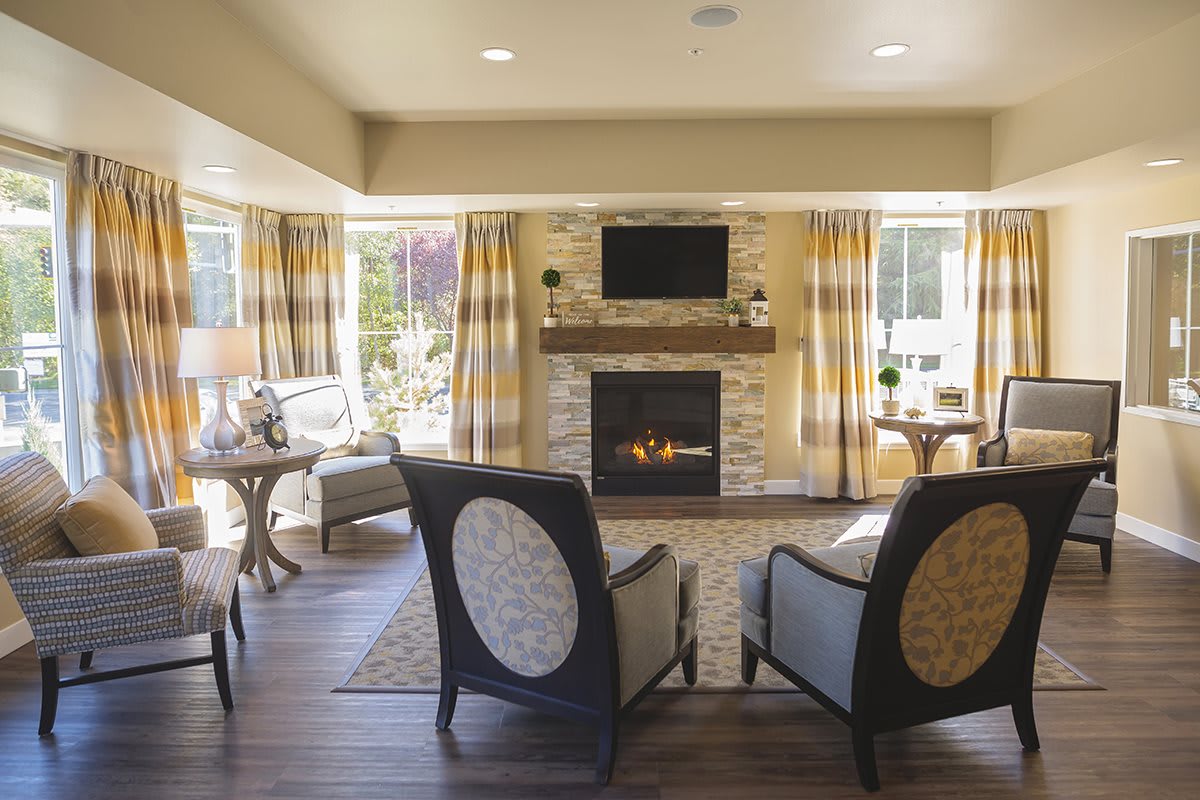 A modern living room with a fireplace and ample seating, featuring large windows that allow natural light to fill the space.