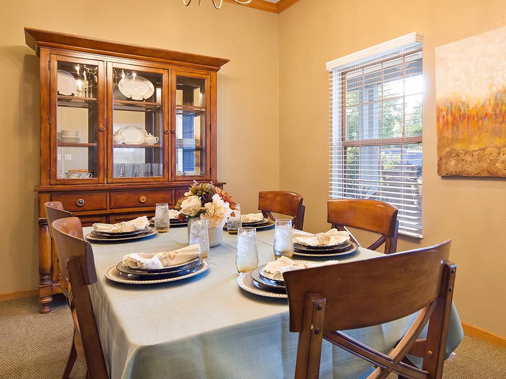 A cozy dining room with a neatly set table and a china cabinet in the background.