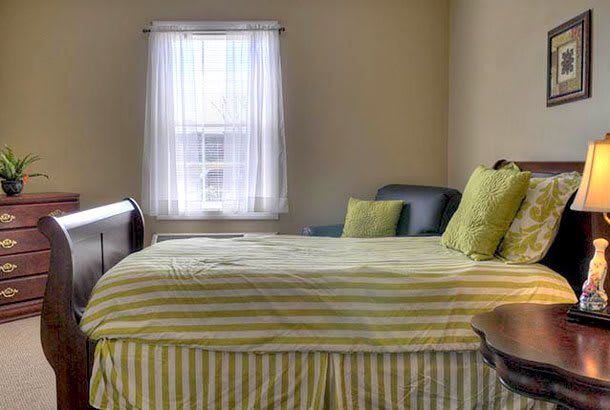 A cozy bedroom with striped bedding and a window letting in natural light.