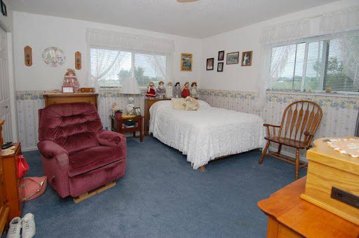A cozy and inviting bedroom with a white bed, plush seating, and personal touches.